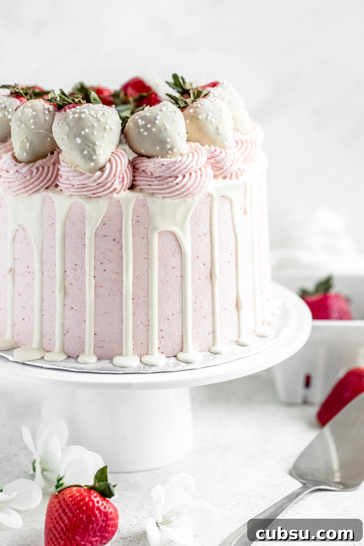 white chocolate and strawberry cake on a white cake stand