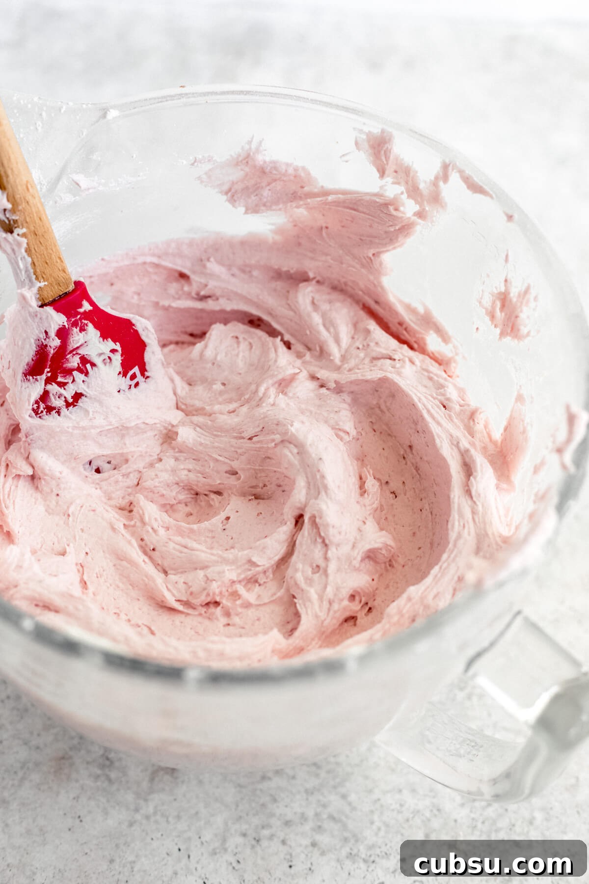 white chocolate strawberry frosting in a glass stand mixer bowl