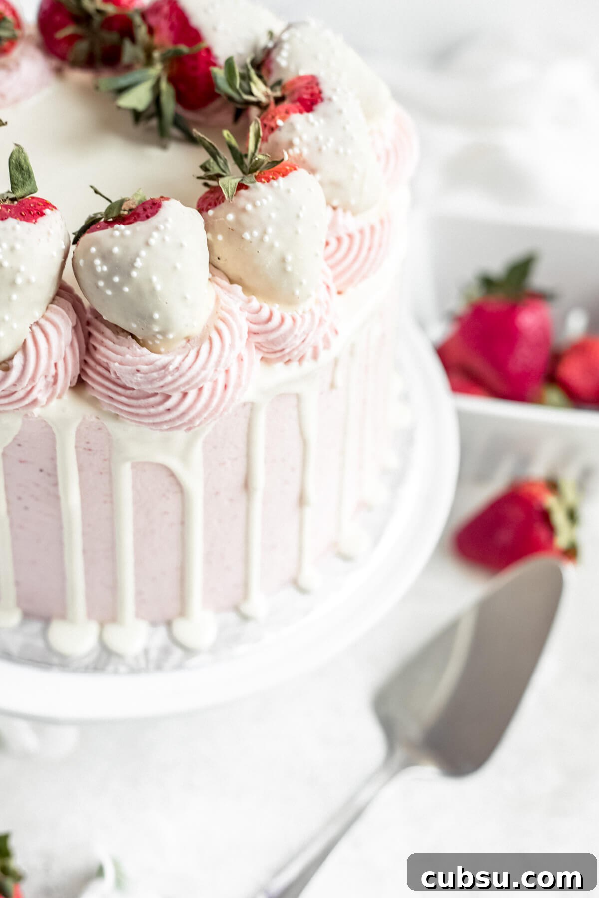 close up of white chocolate covered strawberries on top of a cake