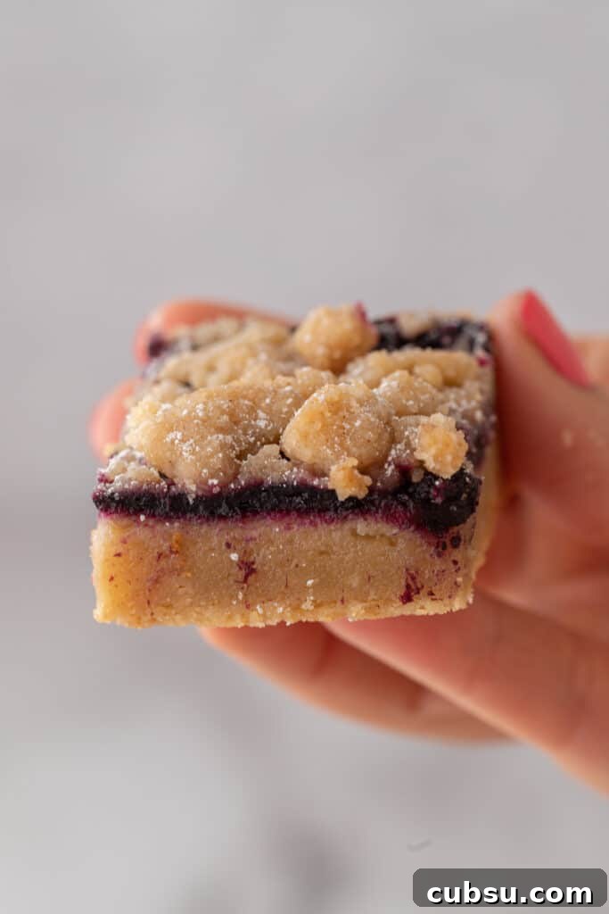 Chewy Blueberry Blondies Recipe with Lemon Glaze 12 blueberry blondies recipe being held up by a hand