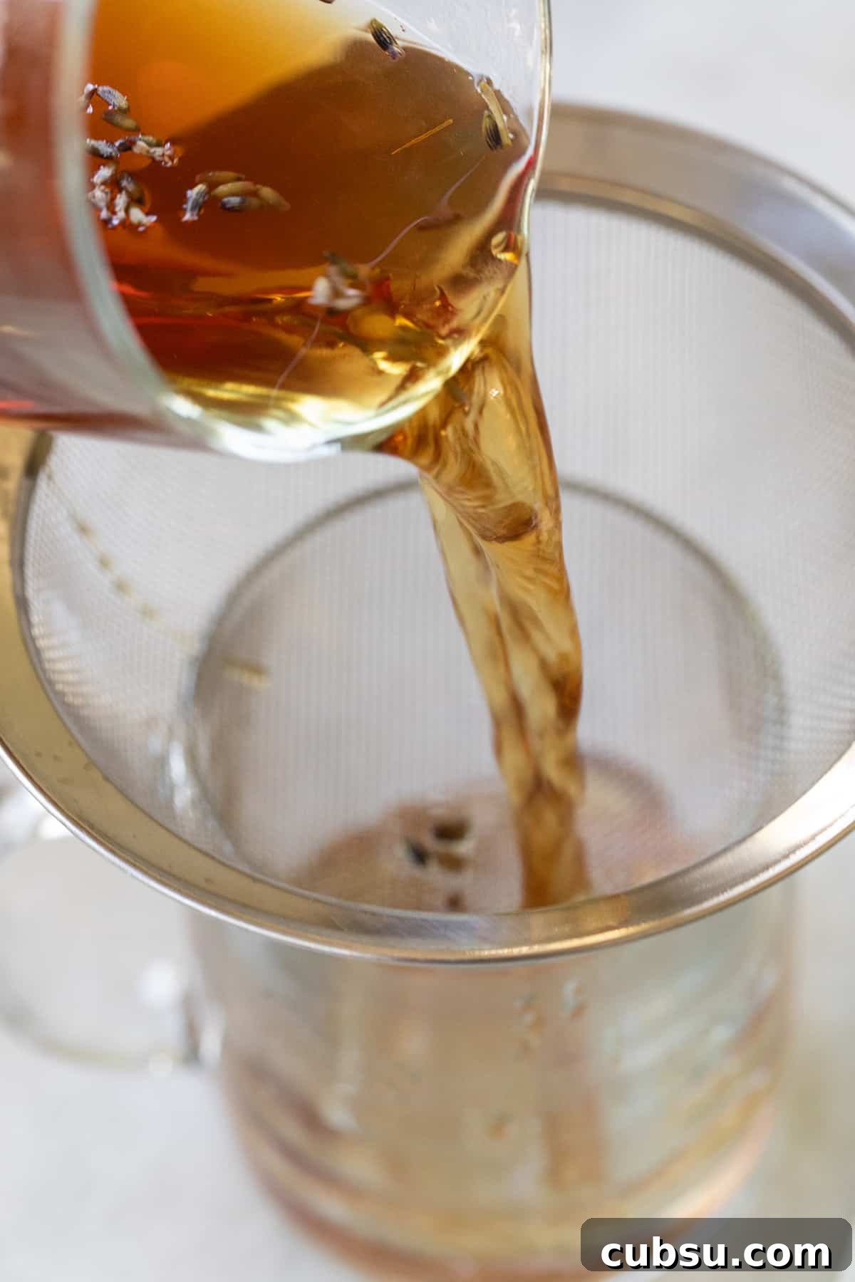 London Fog Latte: Creamy Earl Grey Tea with Vanilla and Lavender 4 Straining Earl Grey tea with lavender into a mug through a mesh strainer.