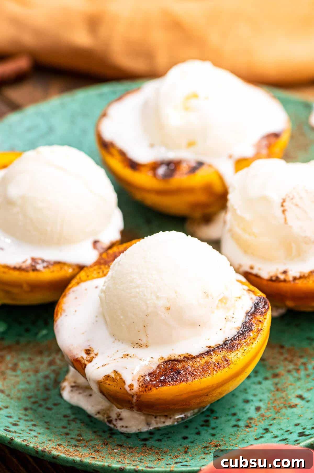 Grilled Peaches with Honey-Balsamic Glaze Recipe 2 Close up image of four peaches halves that are grilled with a scoop of ice cream on top.