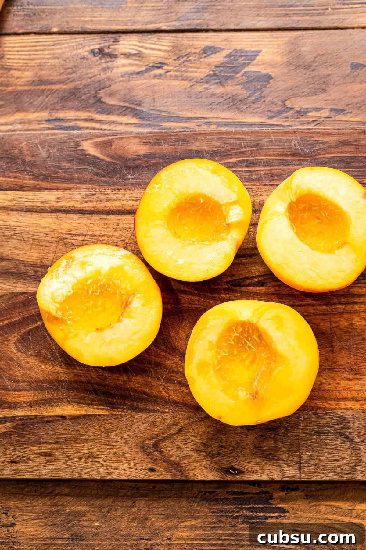 Grilled Peaches with Honey-Balsamic Glaze Recipe 4 Peaches cut in half laying on wooden background.