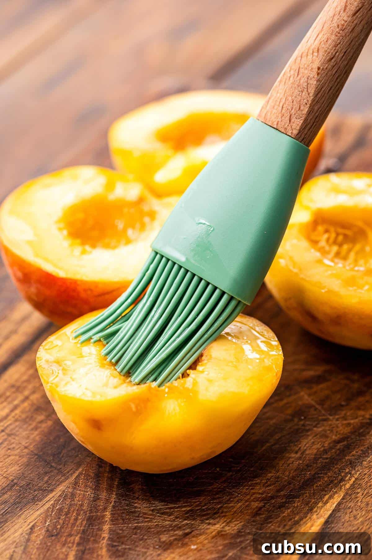 Grilled Peaches with Honey-Balsamic Glaze Recipe 5 Silicone brush basting inside of peach with oil.
