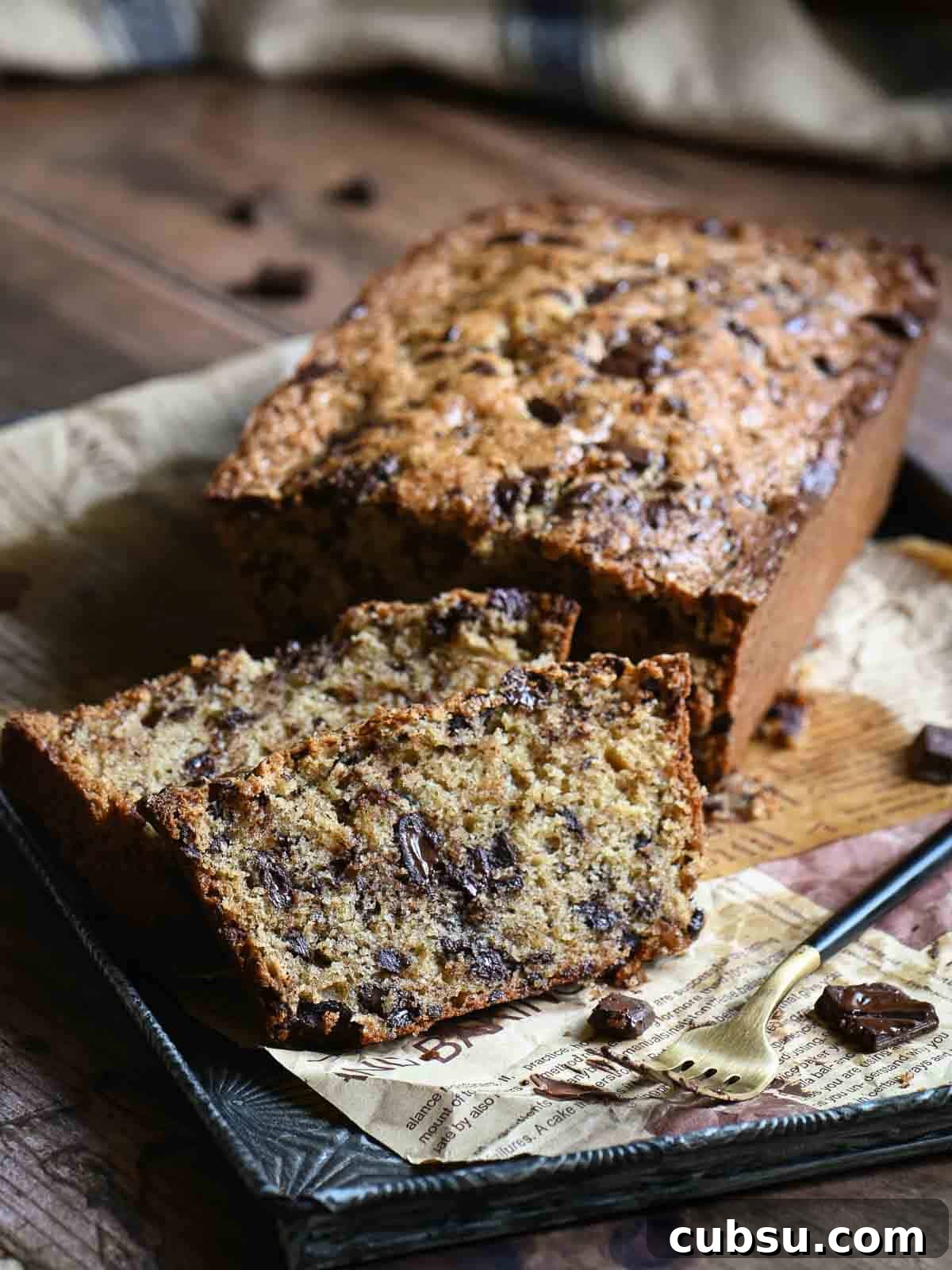 Chocolate chip bread cut with a few slices showing the inside on a wooden board.