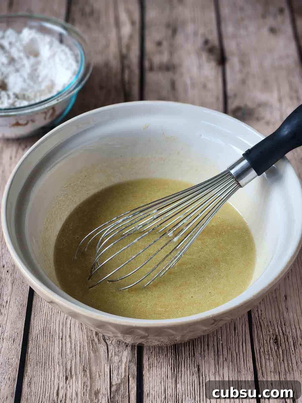 Wet ingredients in a mixing bowl with a whisk.