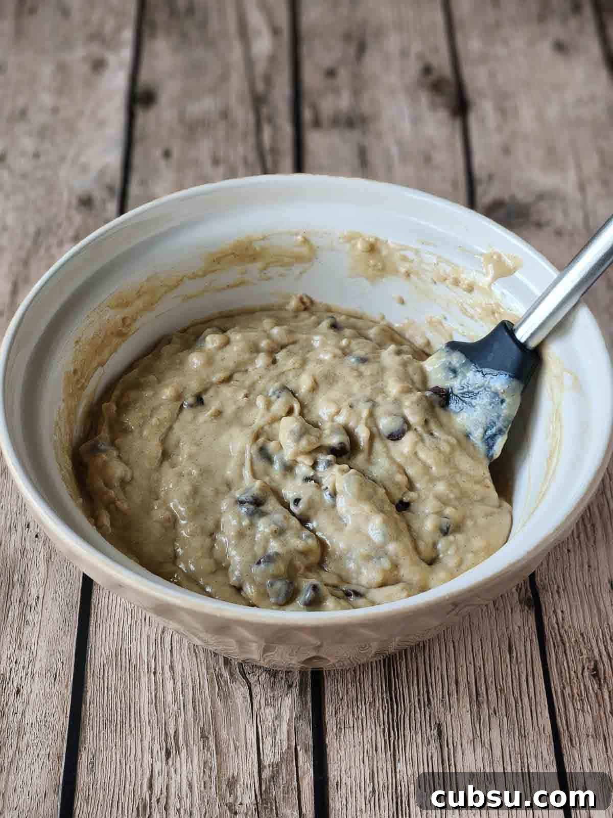 Cake batter with chocolate chips in a beige bowl.