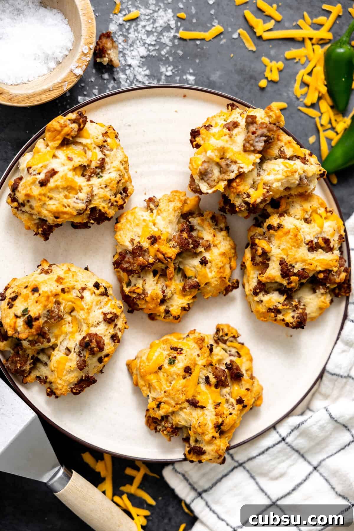 Cheesy Sausage Biscuit Recipe — Flaky Savory Breakfast Biscuits 2 Sausage and cheese drop biscuits on a plate.