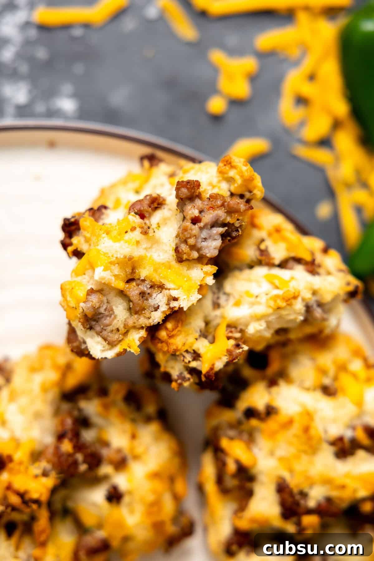 Cheesy Sausage Biscuit Recipe — Flaky Savory Breakfast Biscuits 8 Split apart sausage biscuit on a plate.