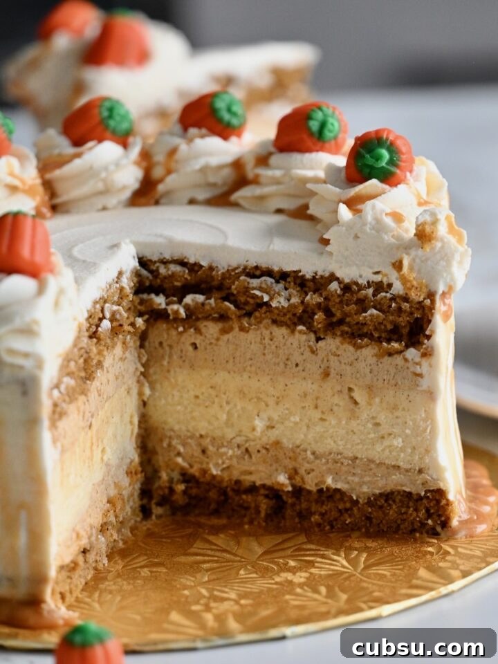 A close-up of a festive pumpkin cake cheesecake layer cake decorated with caramel-drizzled whipped cream swirls and candy pumpkins on top.