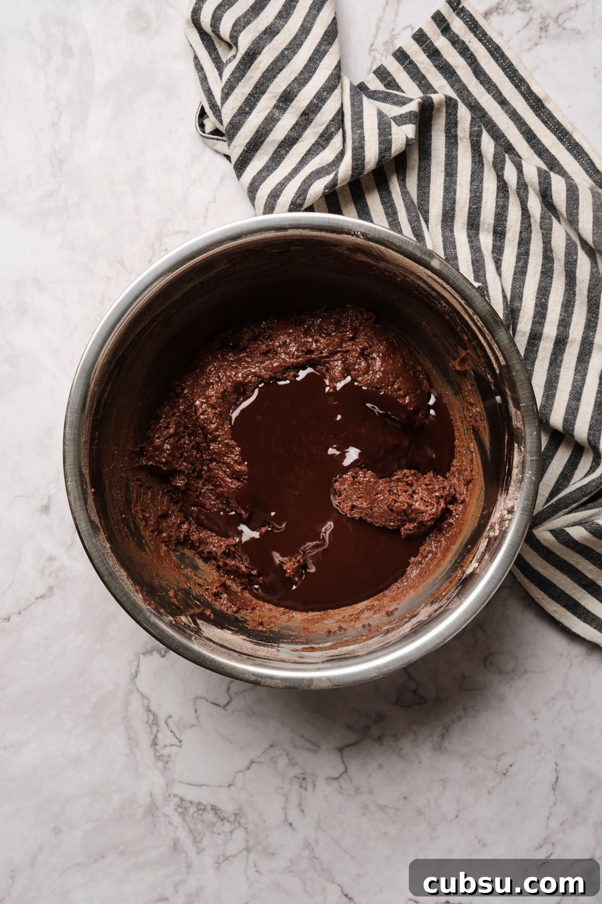 Chocolate Cake with Creamy Peanut Butter Frosting Recipe 8 A bowl of fudgy chocolate cake batter with chocolate butter being mixed in.