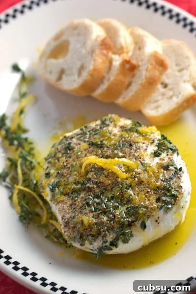 Thyme & Peppercorn Goat Cheese with Lemon Oil Drizzle 2 Plate of goat cheese with herbs and lemon with bread alongside.