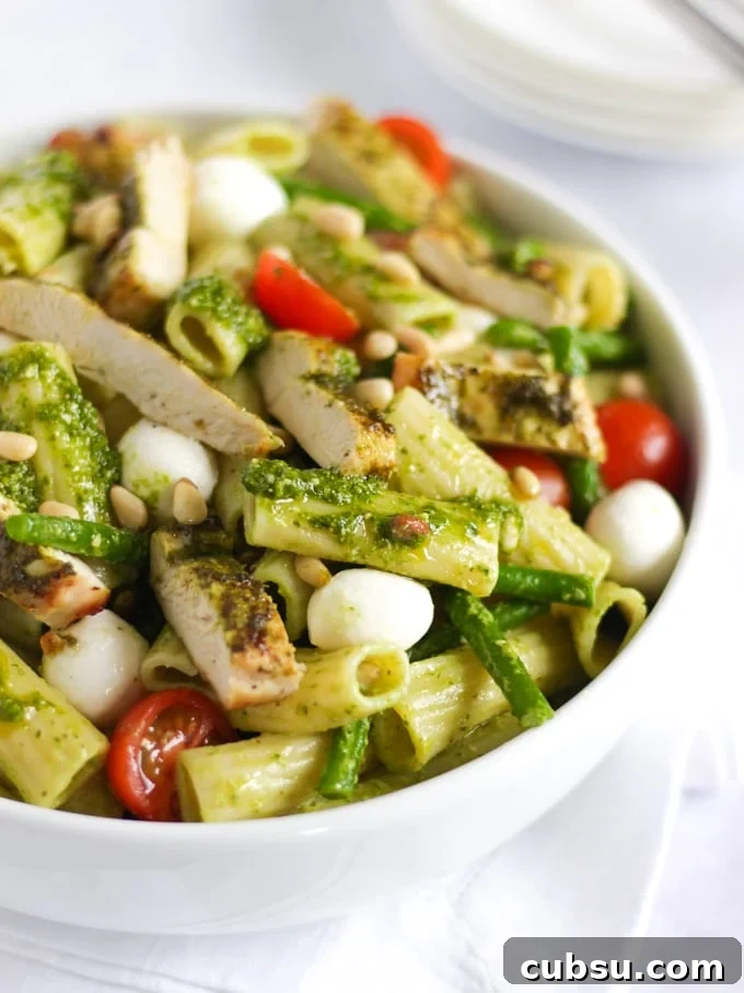 Chicken pesto pasta bake with tomatoes and green beans in a white bowl