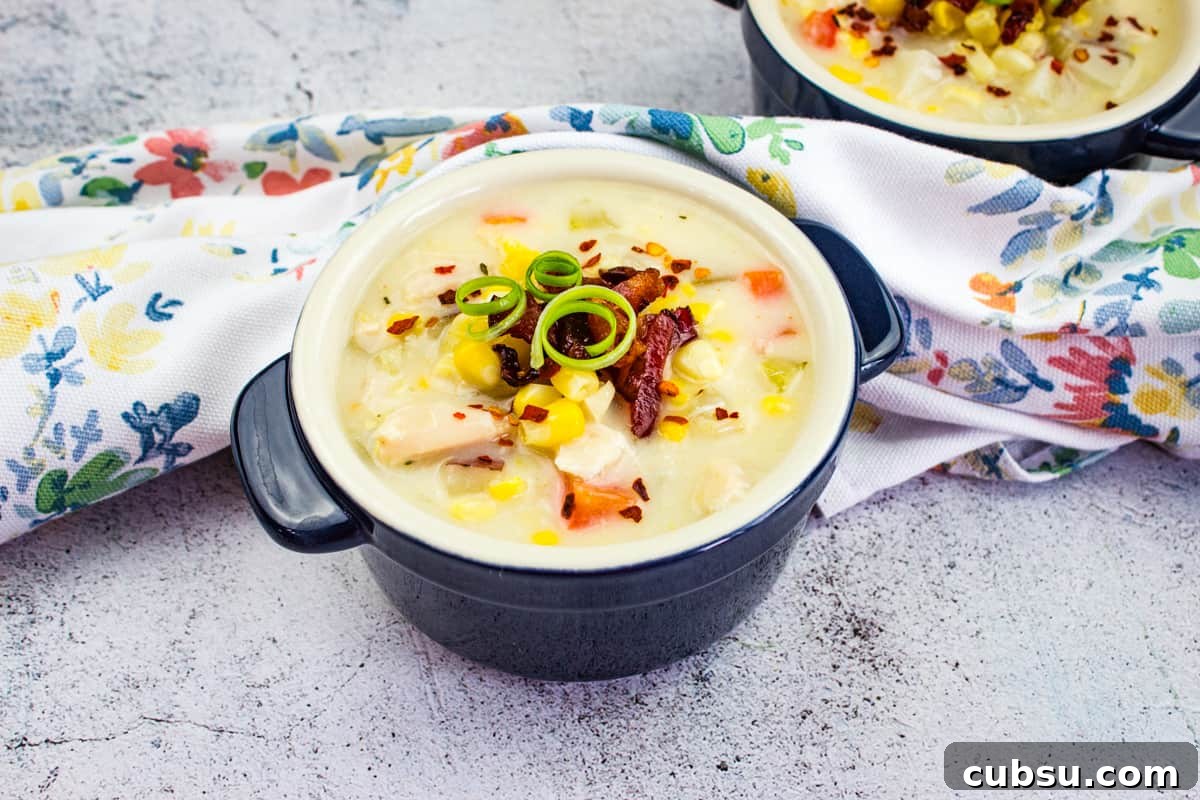 31 Classic Comfort Recipes That Keep Families Coming Back 14 Chicken & Corn Chowder in a black bowl, topped with bacon, scallions, and red pepper flakes.