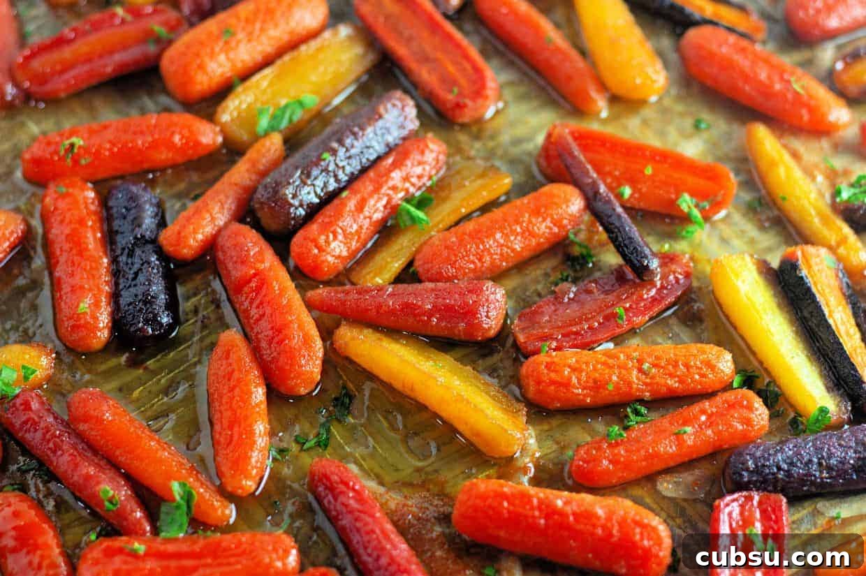 31 Classic Comfort Recipes That Keep Families Coming Back 22 Assorted roasted baby carrots in orange, yellow, and purple colors on a baking sheet, garnished with chopped herbs.