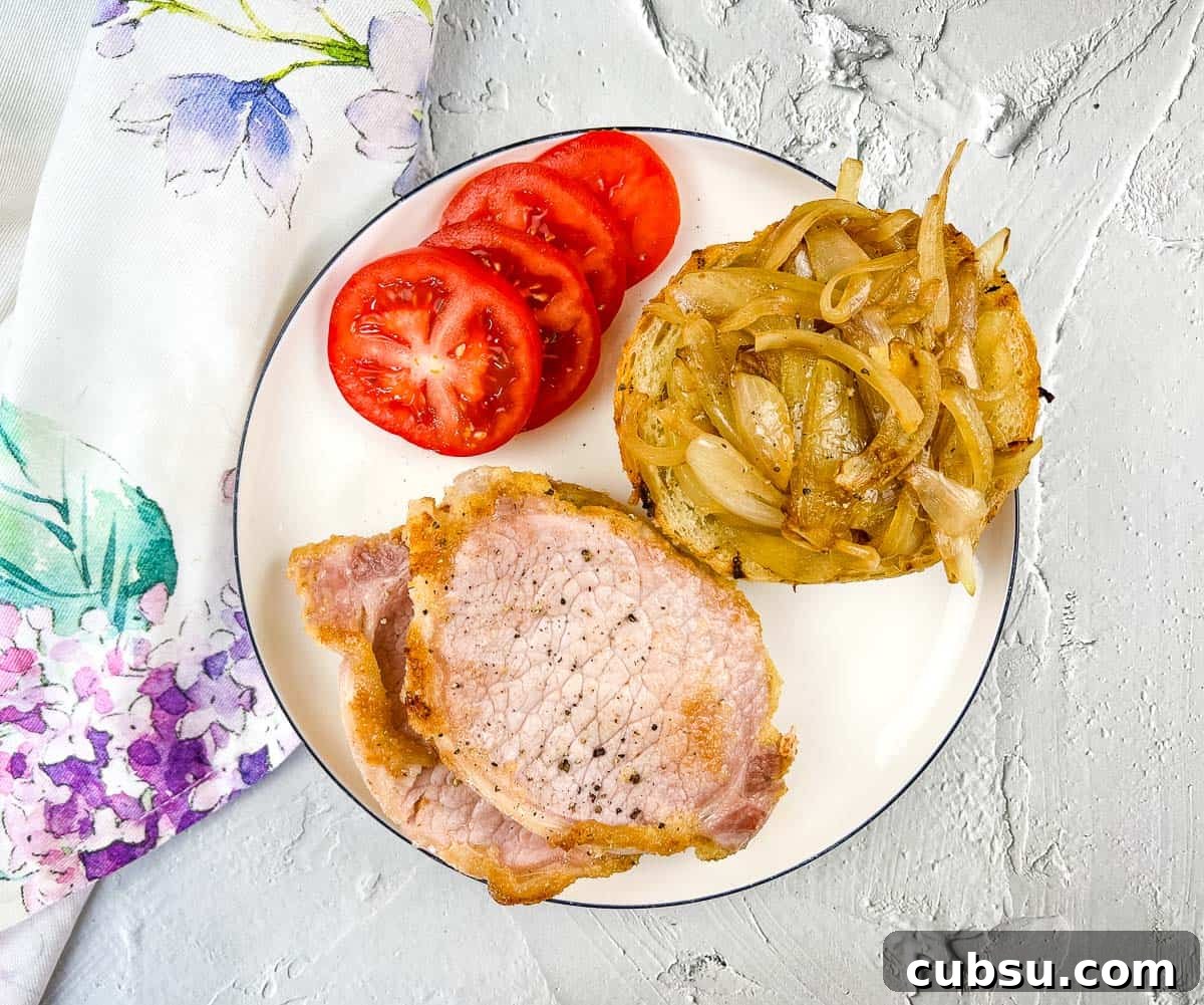 31 Classic Comfort Recipes That Keep Families Coming Back 25 Peameal bacon on a plate with cut tomatoes and cooked onions.