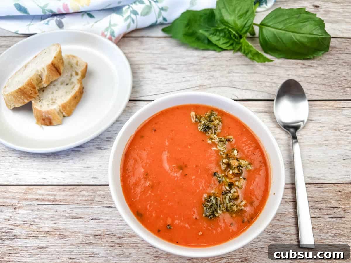 31 Classic Comfort Recipes That Keep Families Coming Back 29 A bowl of red pepper and tomato soup next to a plate of bread and a spoon.