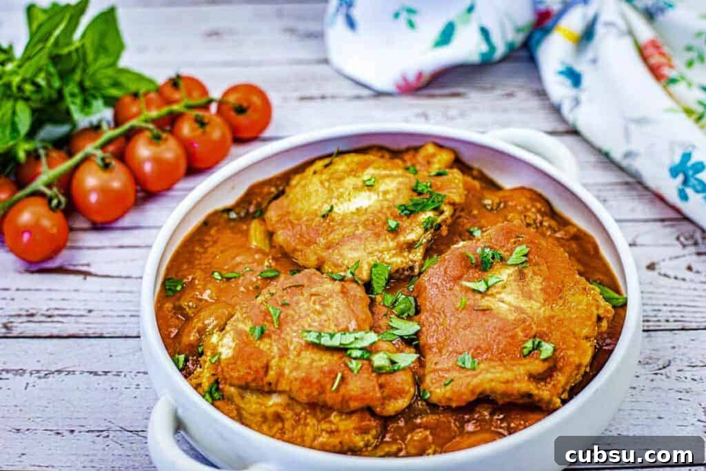 31 Classic Comfort Recipes That Keep Families Coming Back 32 A white dish filled with pieces of Chicken Cacciatore in a red sauce, garnished with chopped herbs.