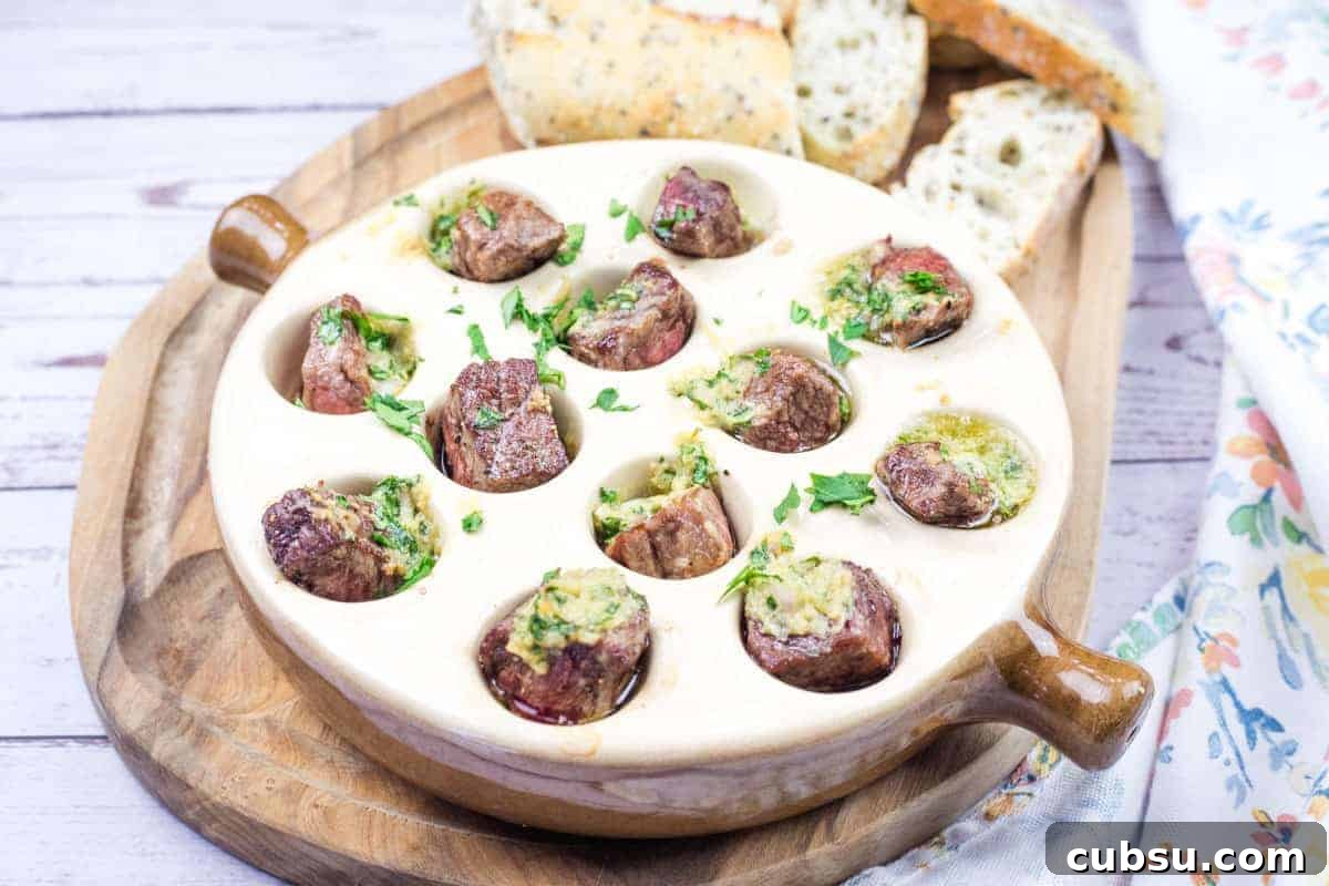 31 Classic Comfort Recipes That Keep Families Coming Back 6 Garlic Butter Steak Bites Escargot-Style dish in a round ceramic plate with cooked snails topped with herbs and butter sauce, and slices of bread on a wooden board.