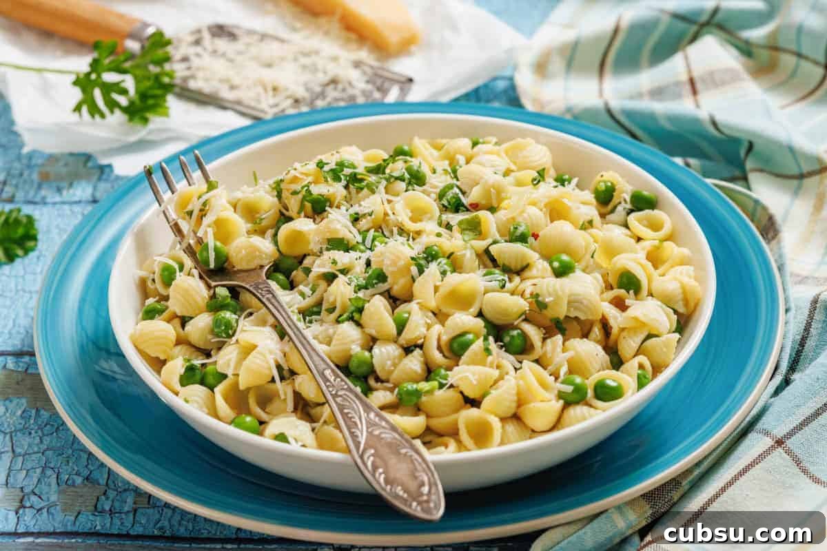 31 Classic Comfort Recipes That Keep Families Coming Back 8 A bowl of pasta and peas with a fork, grater, and cheese on the side.
