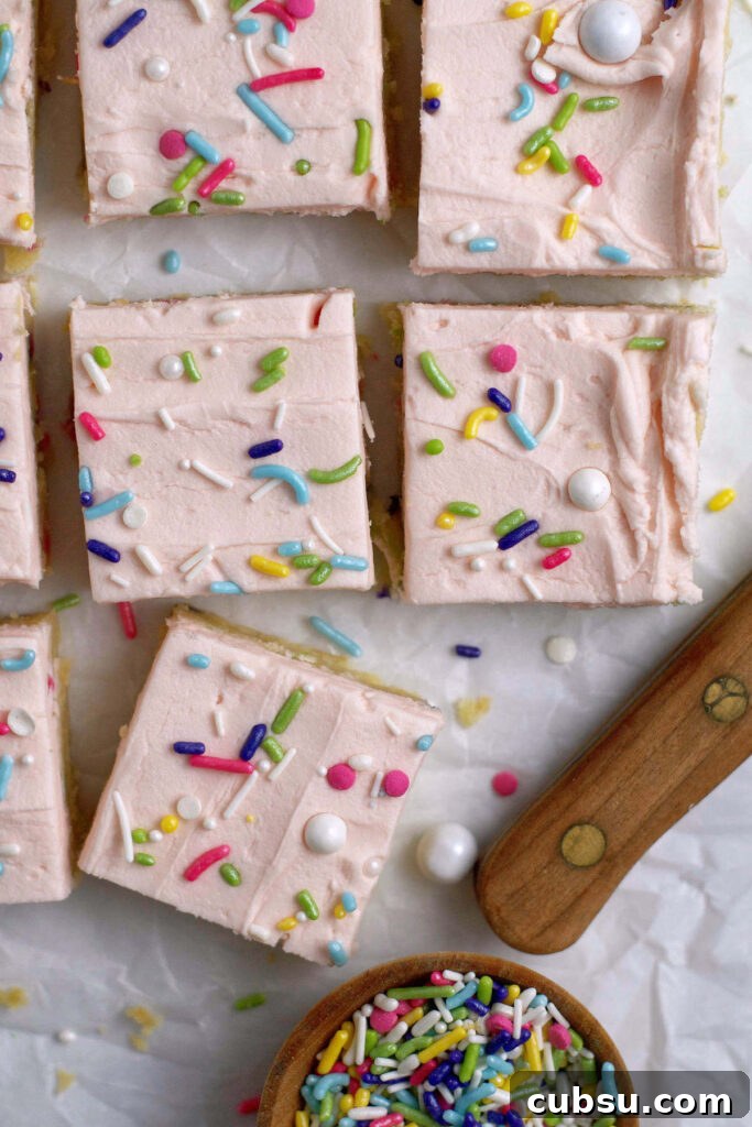 Cream Cheese Sugar Cookie Bars — Soft Frosted Dessert Bars 12 cut sugar cookie bars on parchment paper with extra sprinkles