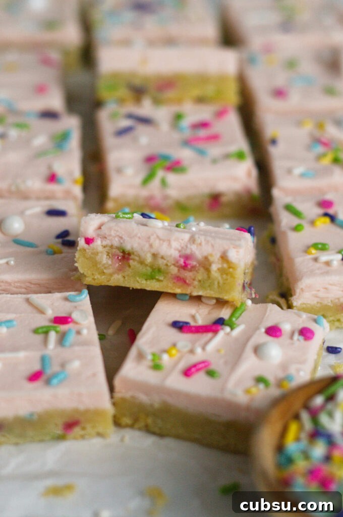 Cream Cheese Sugar Cookie Bars — Soft Frosted Dessert Bars 3 buttercream sugar cookie bars with sprinkles on parchment paper