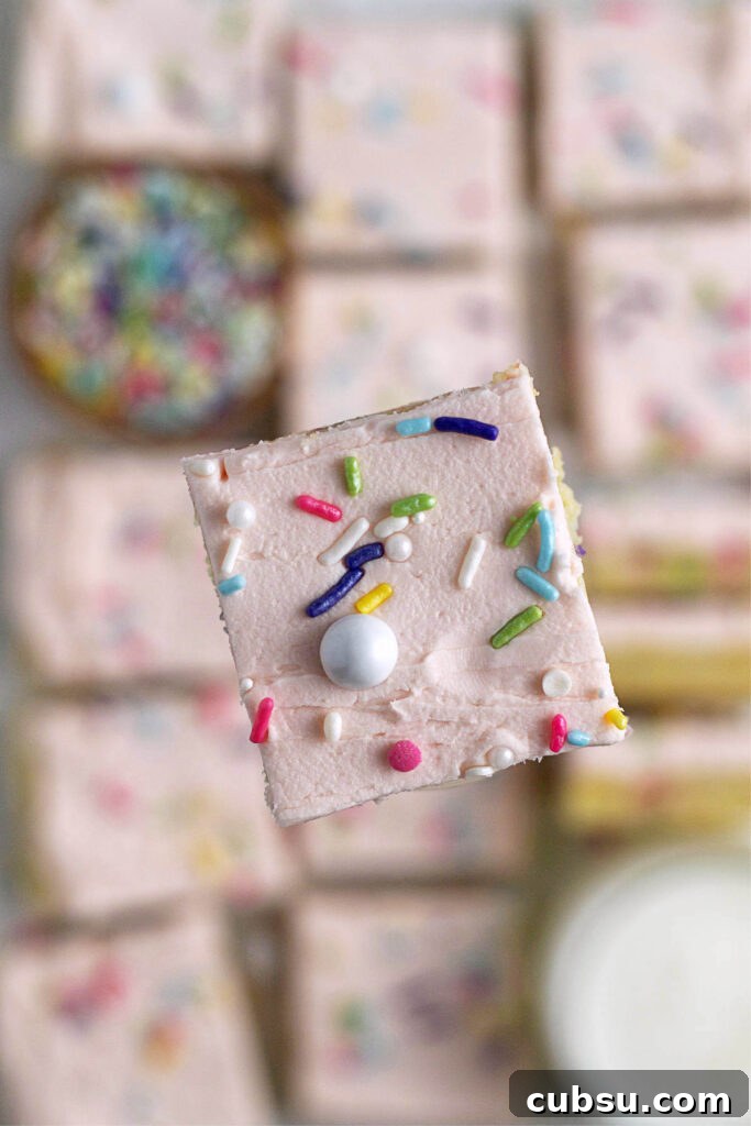 Cream Cheese Sugar Cookie Bars — Soft Frosted Dessert Bars 5 a floating sugar cookie bar with milk and sprinkles blurred underneath