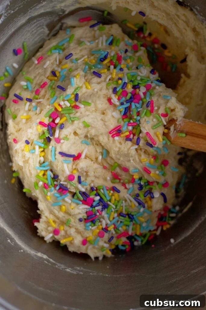 Cream Cheese Sugar Cookie Bars — Soft Frosted Dessert Bars 9 sprinkles on top of sugar cookie bar dough