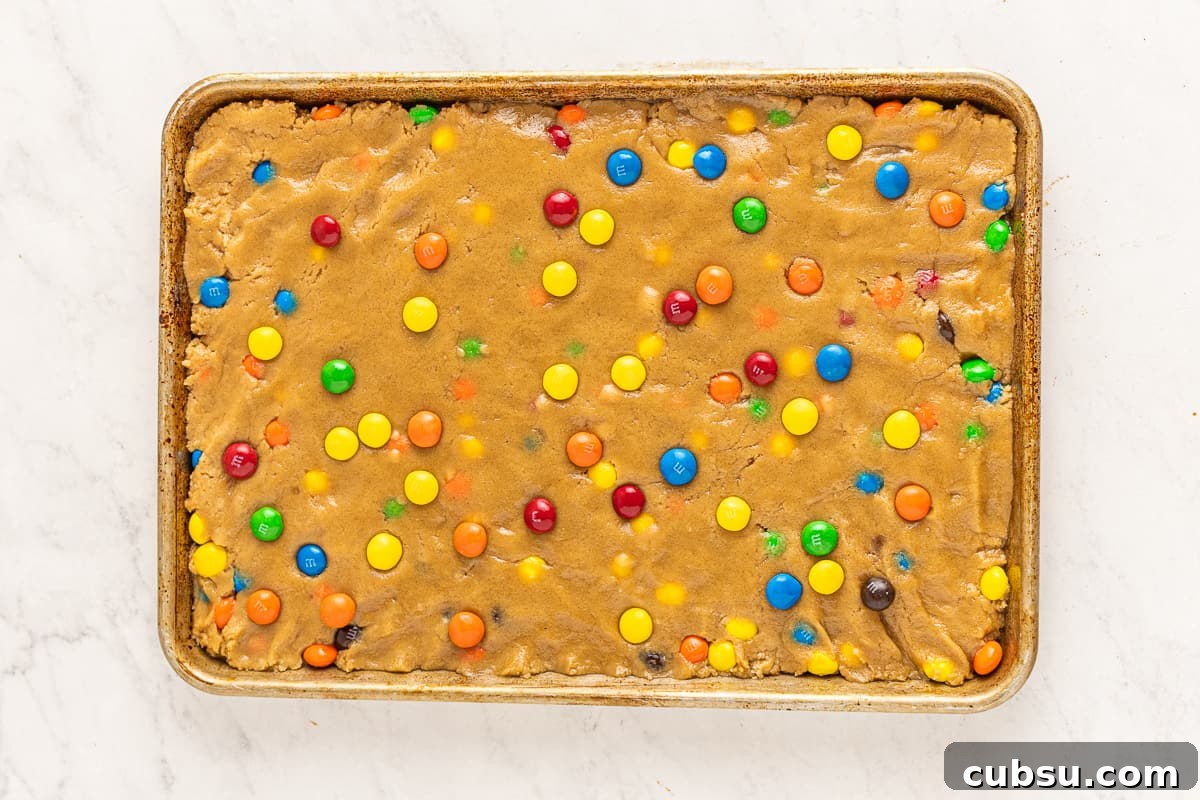 M&M Blondies Recipe: Chewy Chocolate Candy Bar Blondies 8 Peanut butter blondie dough spread into a baking sheet, dotted with M&Ms.