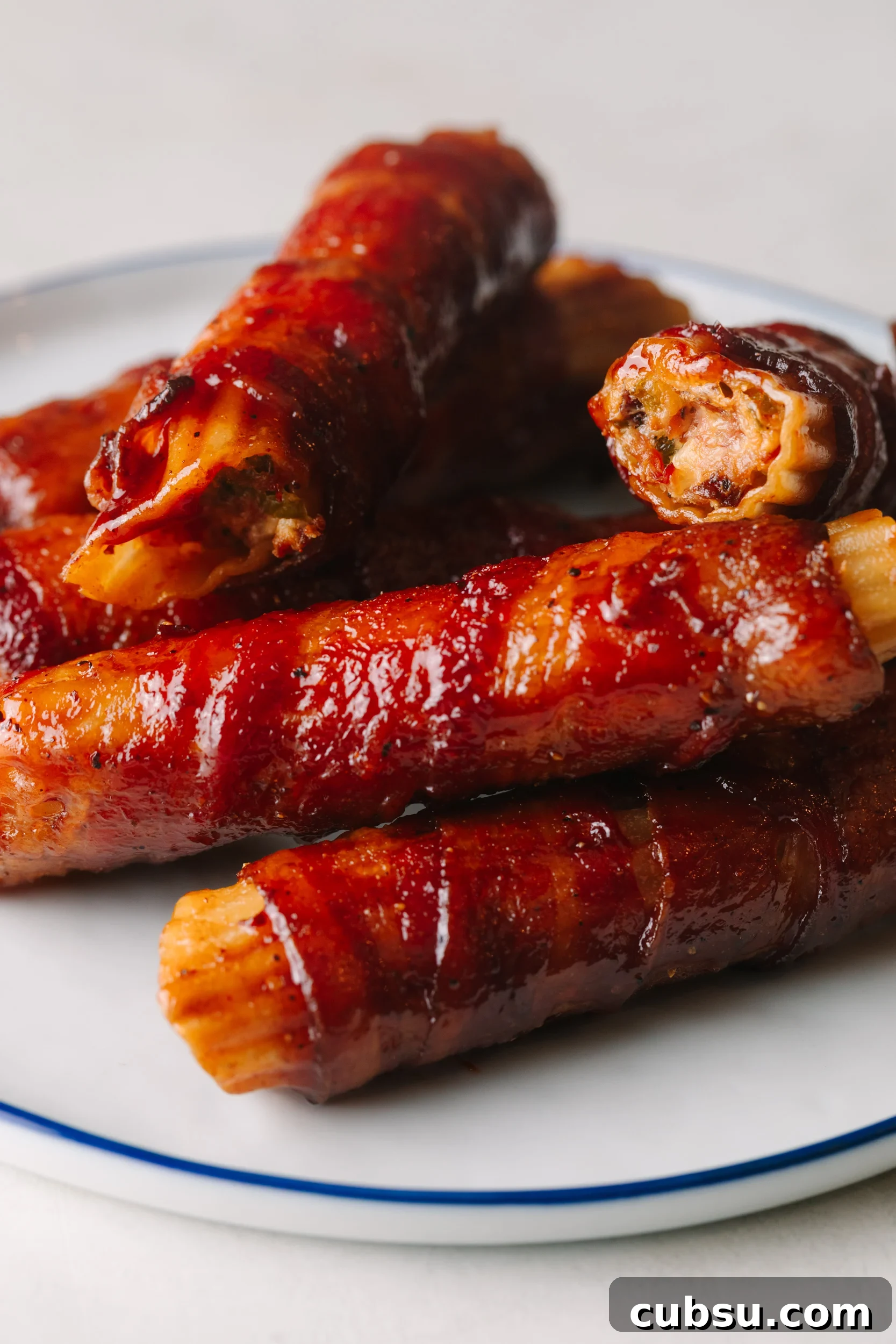 Smoked Shotgun Shells: How They're Made and What to Know 2 Pulled pork smoked shotgun shells drizzled with bbq sauce on a white plate.