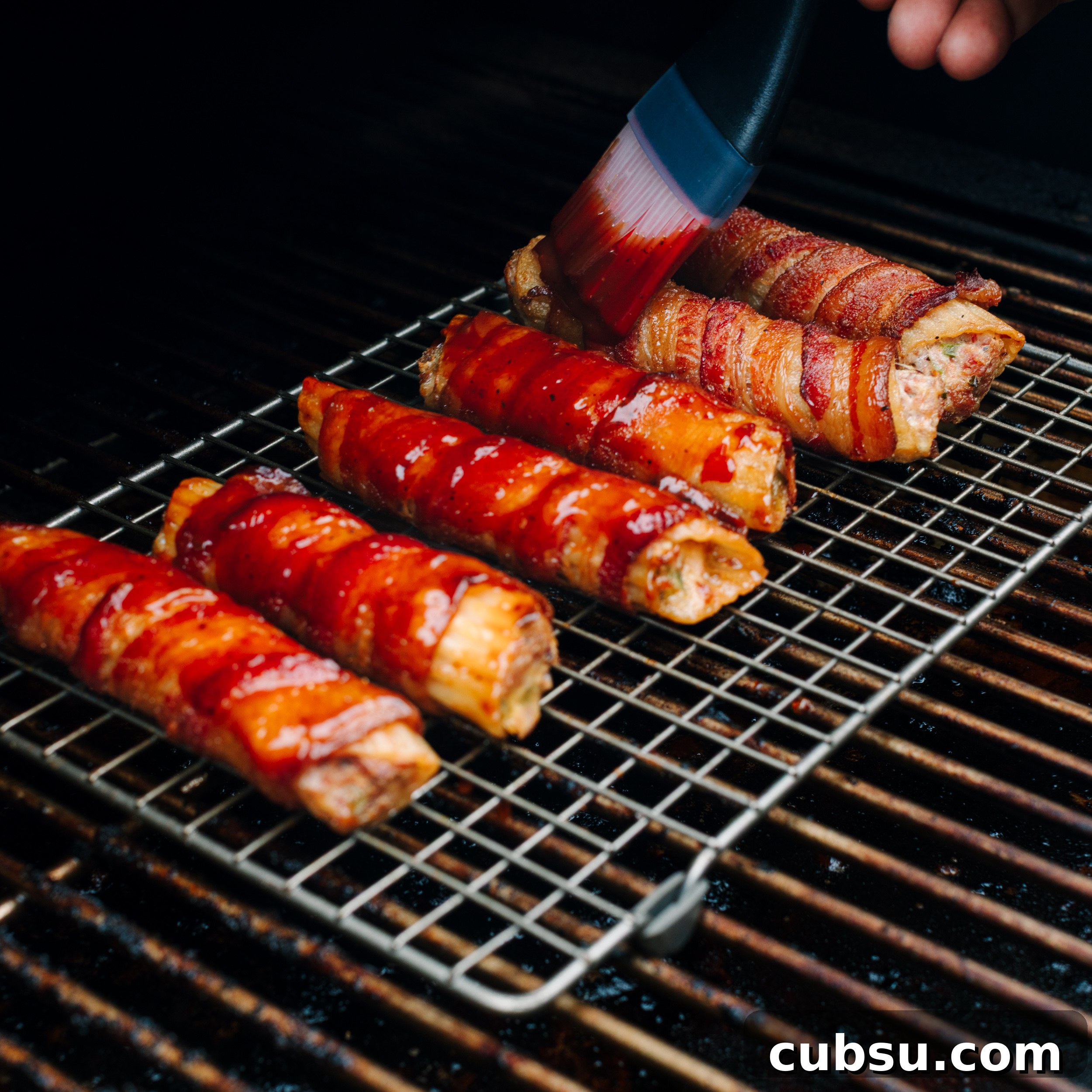 Smoked Shotgun Shells: How They're Made and What to Know 8 Smoked shotgun shells on a wire rack on a smoker being basted with BBQ sauce.