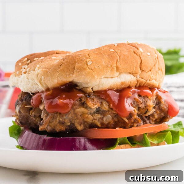 Blackstone Meatloaf Burger topped with ketchup, tomatoes and red onions on a plate.