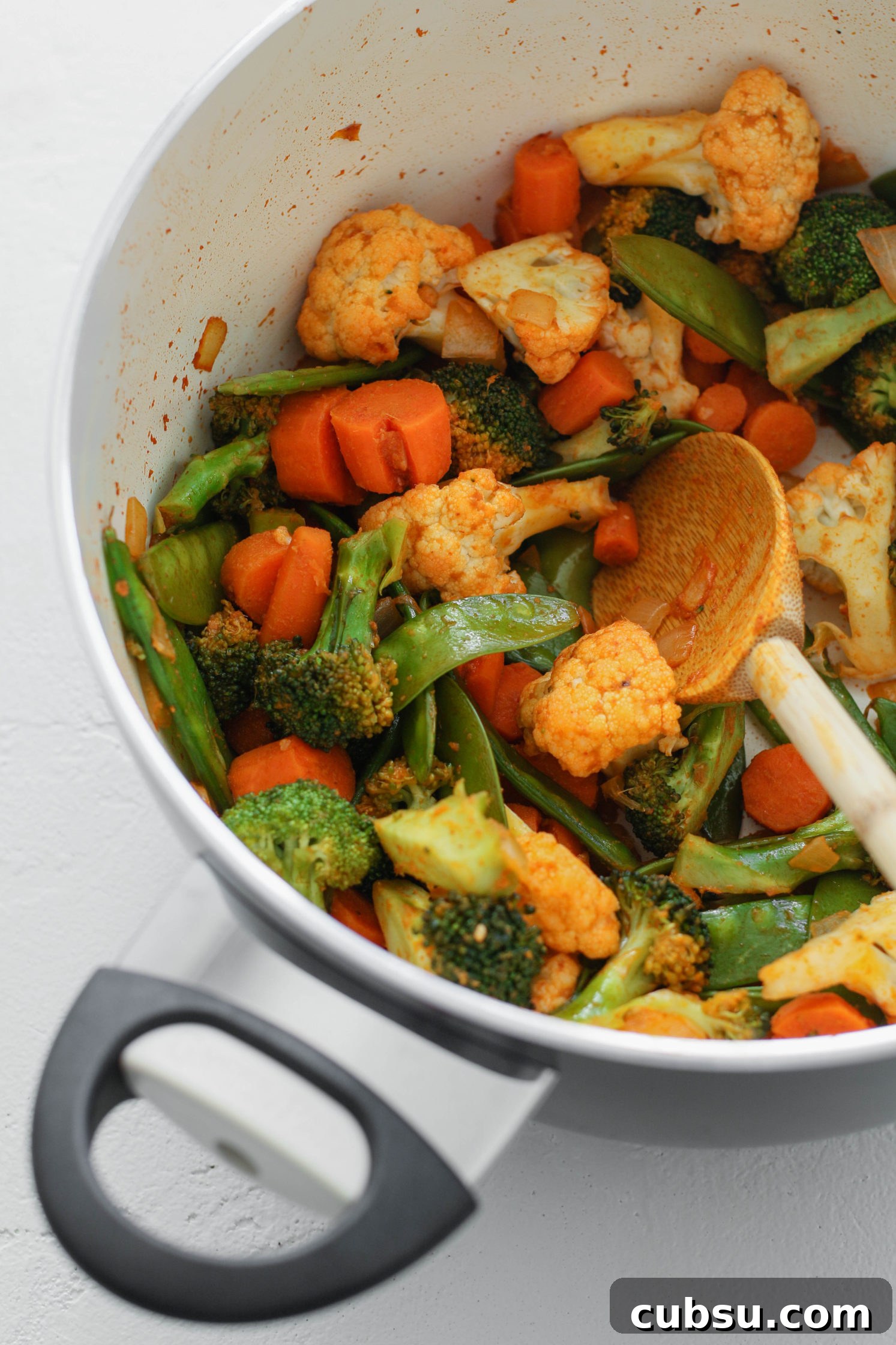 curry vegetables in a pot with a wooden spoon by Flora & Vino