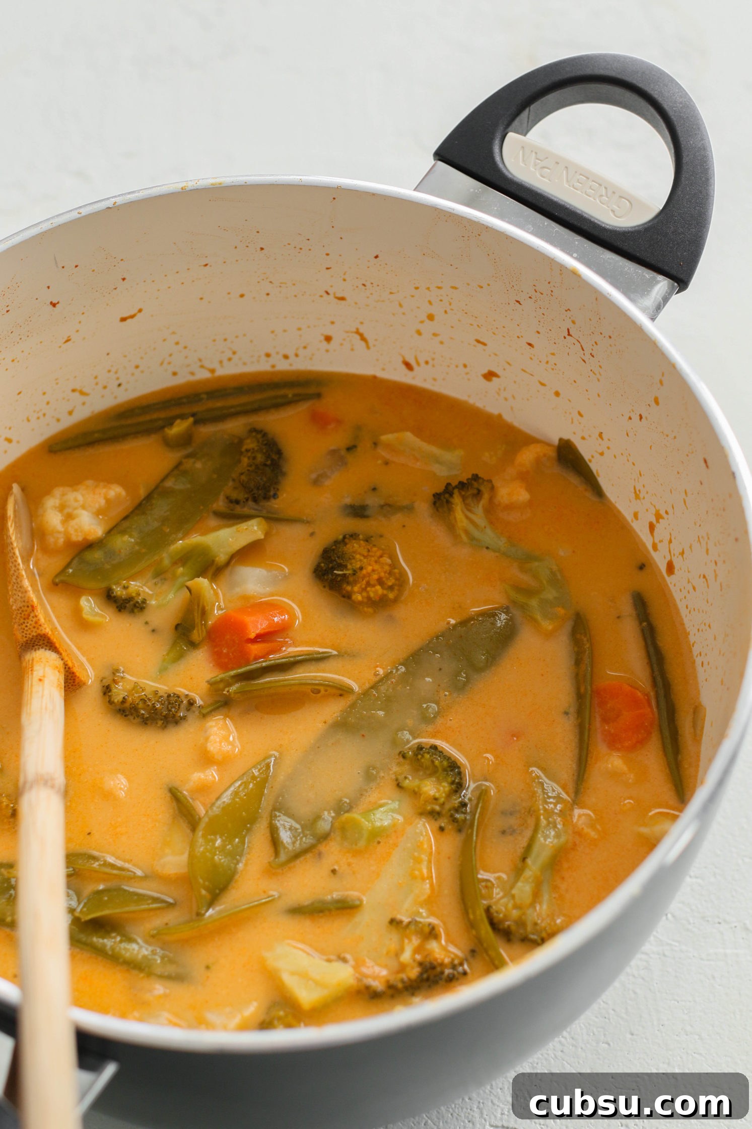 The Quickest Vegan Curry in a pot with a wooden spoon by Flora & Vino