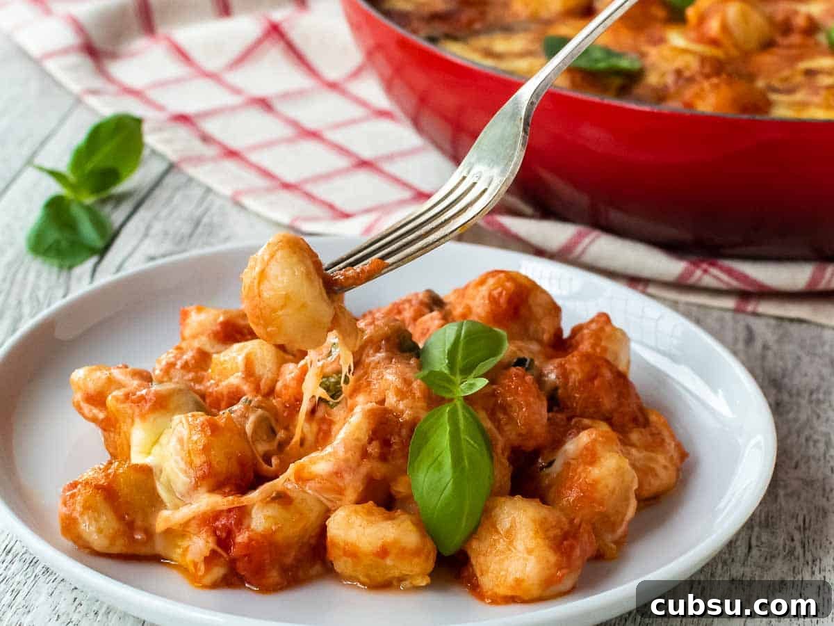 Closeup of gnocchi on a white plate with a fork picking up gnocchi.