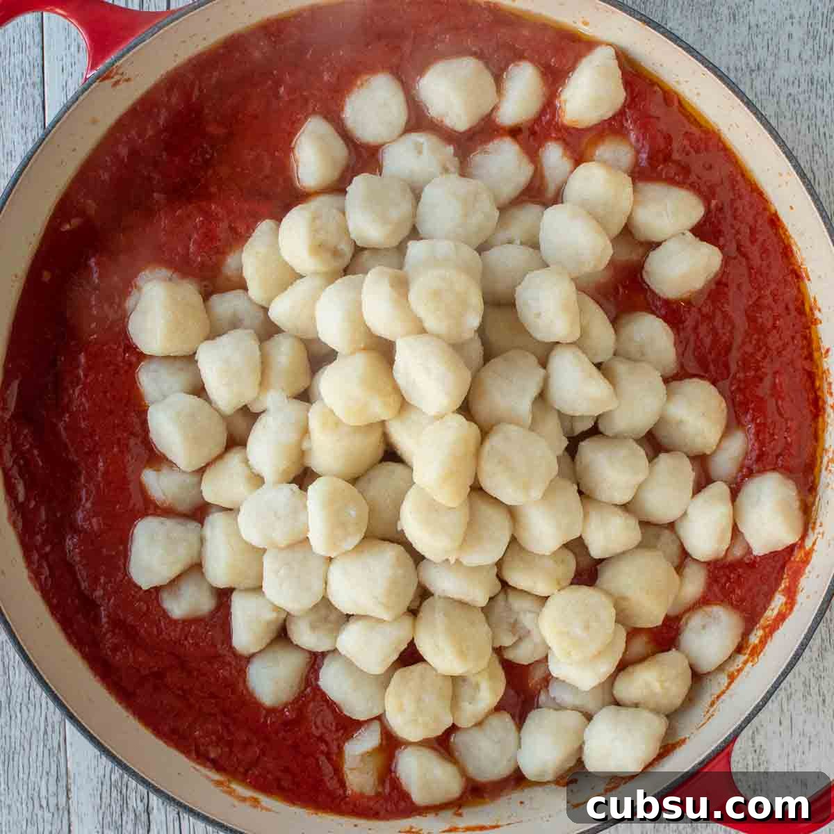 Overhead view of gnocchi on top of tomato sauce.