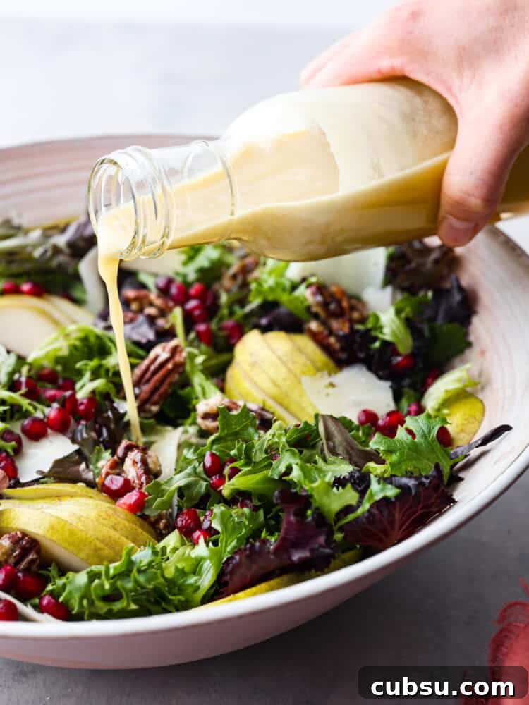 A bottle of champagne vinaigrette being poured onto the salad.
