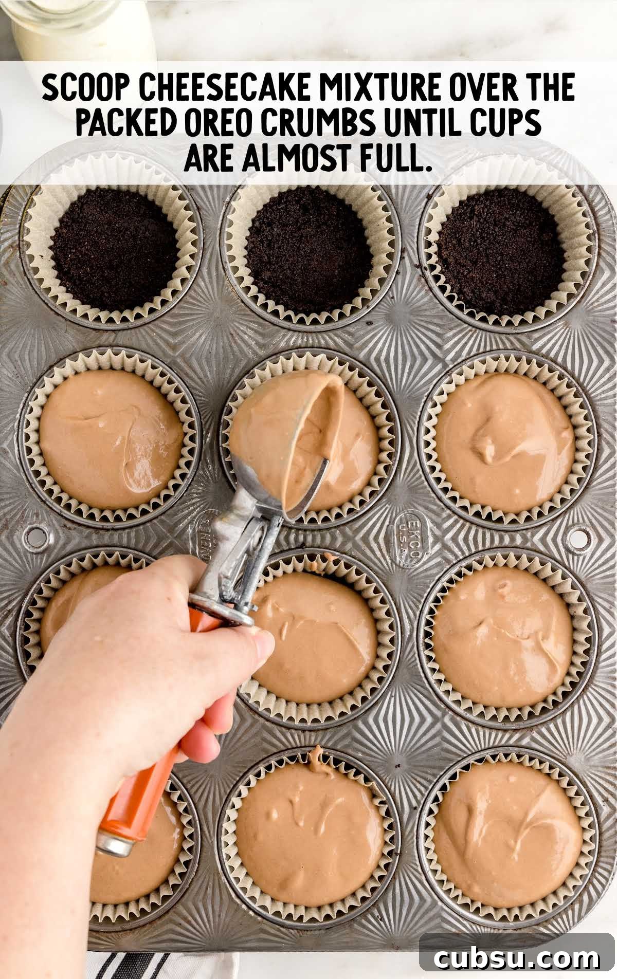 cheesecake mixture scooped over the oreo crumbs in a cupcake baking tray