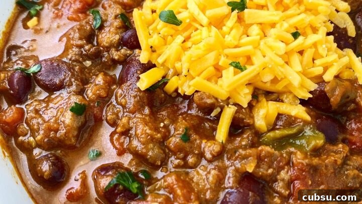 side view close up shot of pumpkin chili in a white bowl with a silver spoon