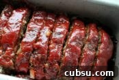 Slice meatloaf with a ketchup glaze on top in a loaf pan