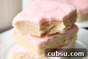 A white plate with a stack of three sugar cookie bars stacked on top of each other with a bite out of a corner of the top bar.