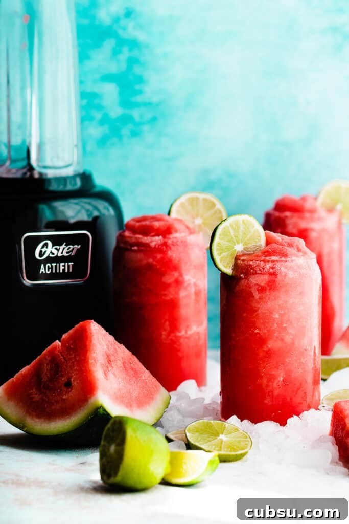 Three glasses of watermelon margaritas with a blender in the background.