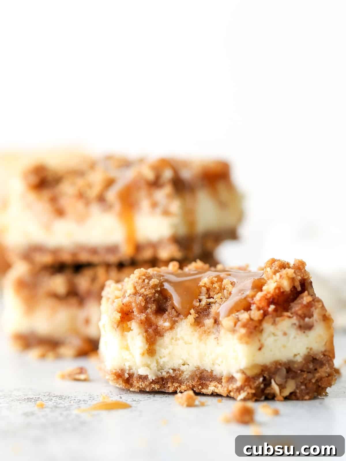 Layers of graham cracker streusel, smooth cream cheese filling, cinnamon apple chunks, and caramel drizzle make up these rich and creamy caramel apple cheesecake bars.