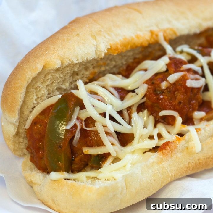 Meatball sub with sauce, cheese, and peppers on a bun.