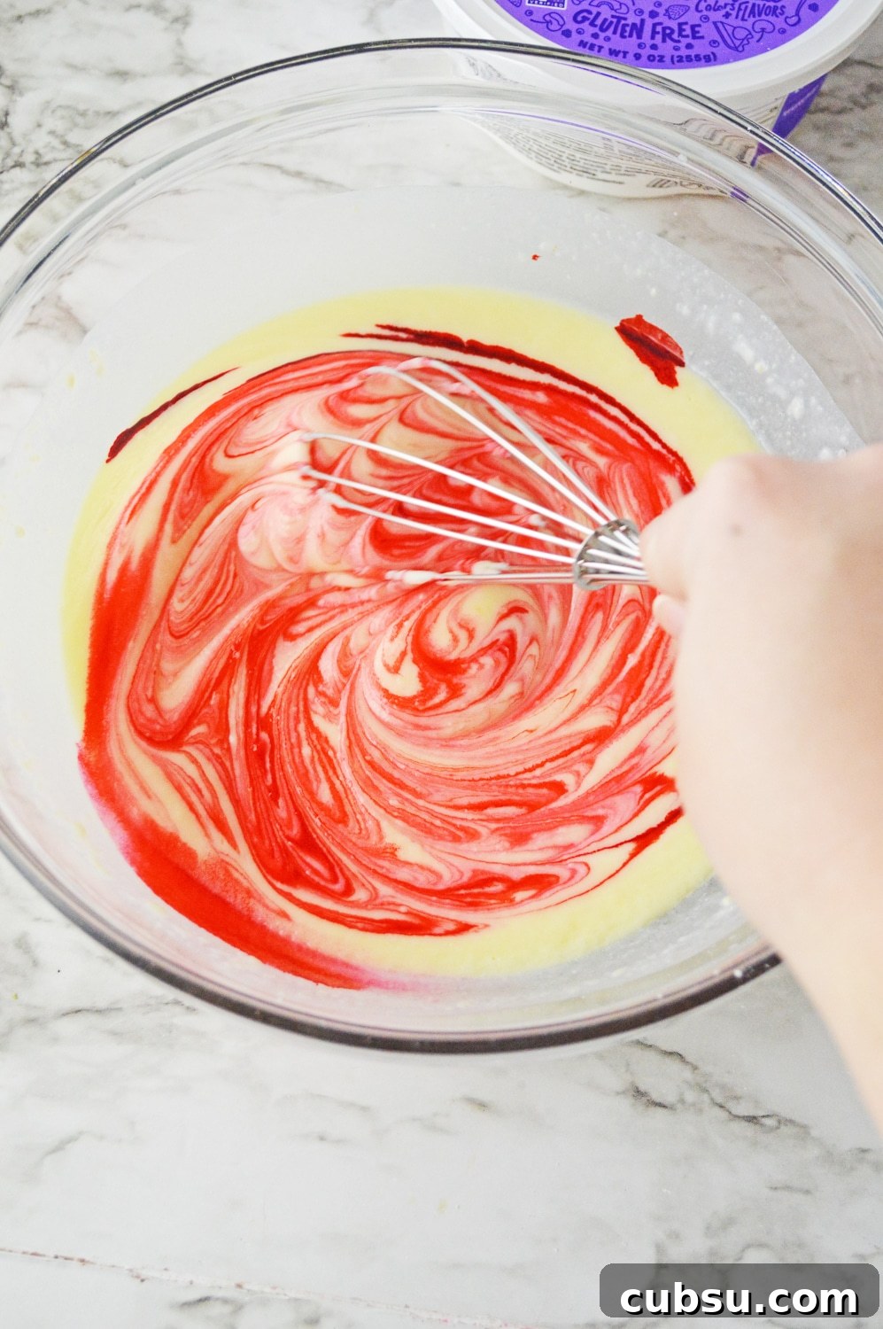 adding red food coloring to bowl of pudding mix