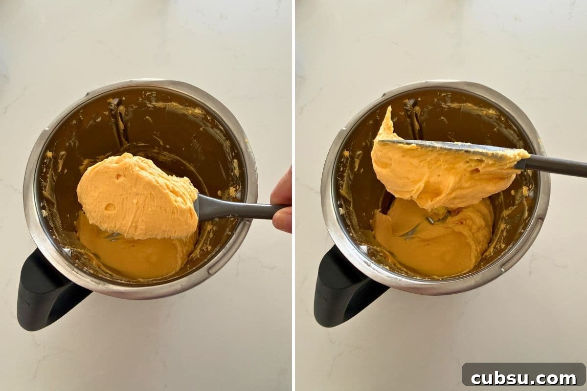 Blended cheddar butter on a spatula over a food processor showing texture.