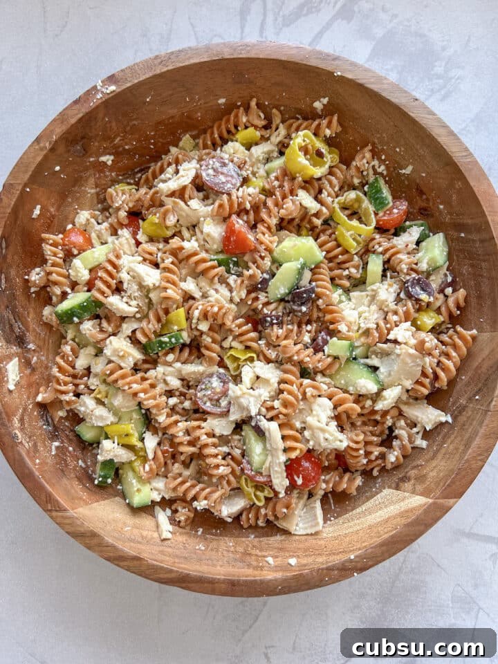 High protein pasta salad in a large wooden bowl, mixed with dressing.