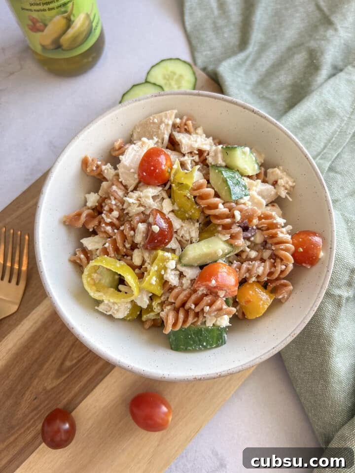 small bowl of protein pasta salad on a wood cutting board, styles with a green kitchen towel and wood cutting board