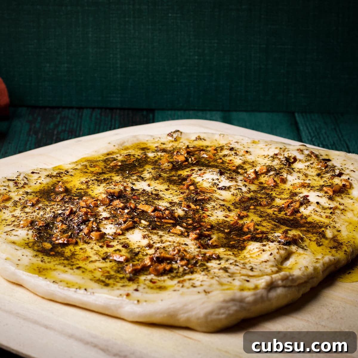Pizza dough that's been covered in garlic herb oil.