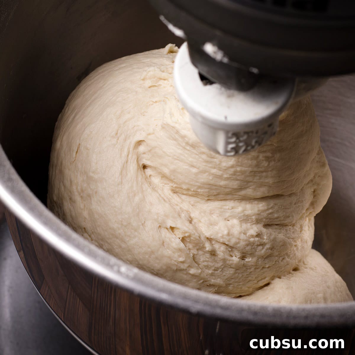 A stand mixer fitted with the dough hook, kneading pizza dough.